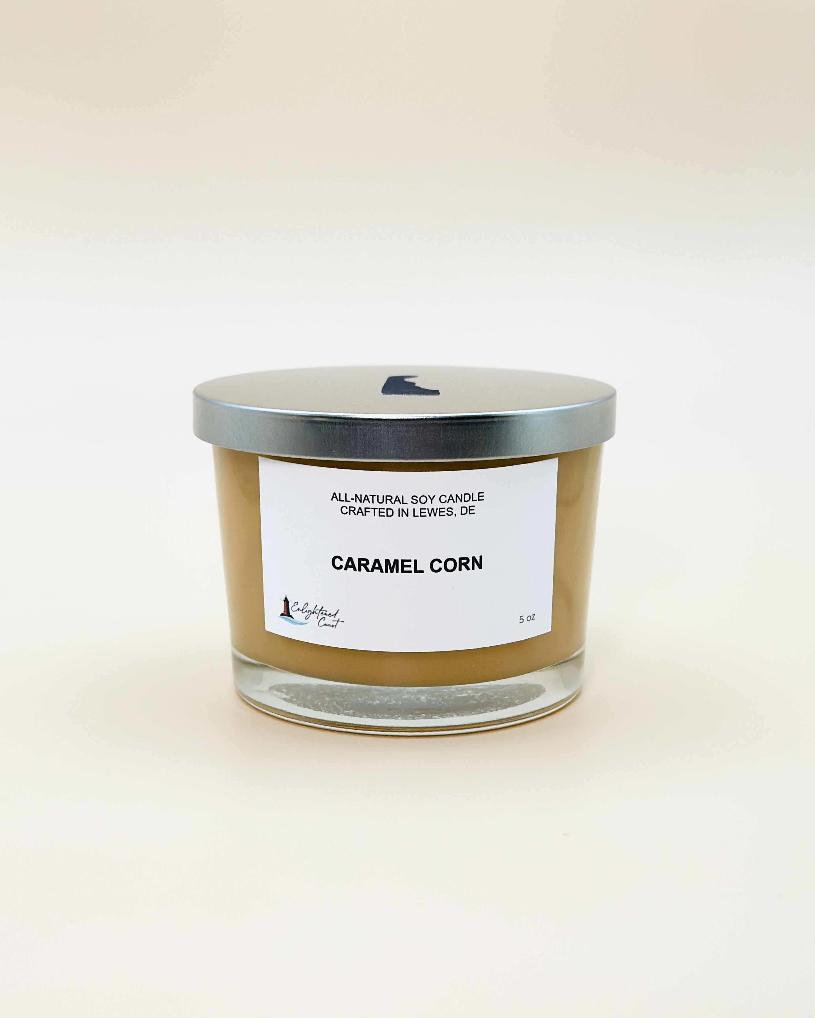 Candle labeled 'Caramel Corn' with a silver lid on a white background