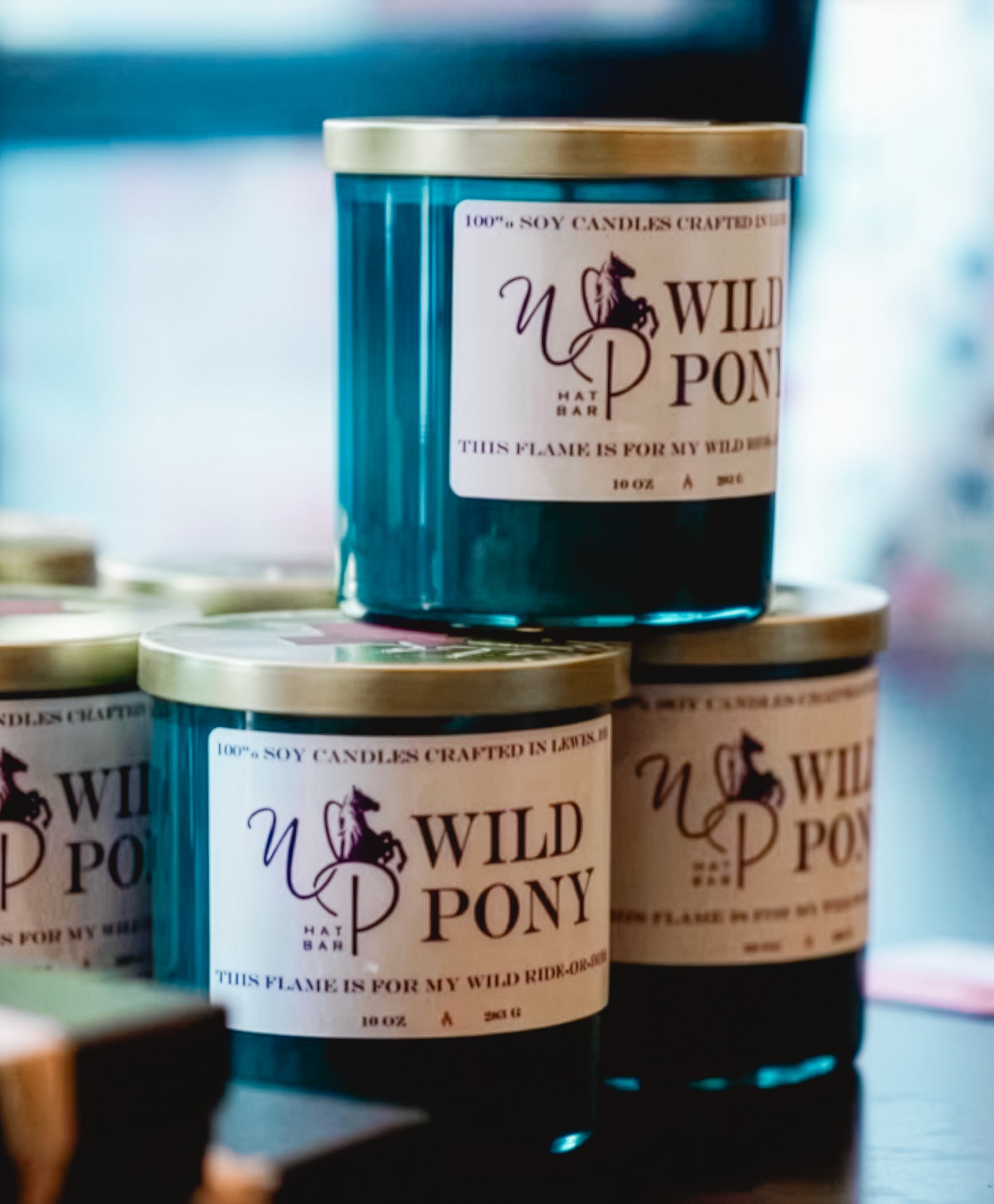 Stack of Wild Pony candles with visible branding on a blurred background