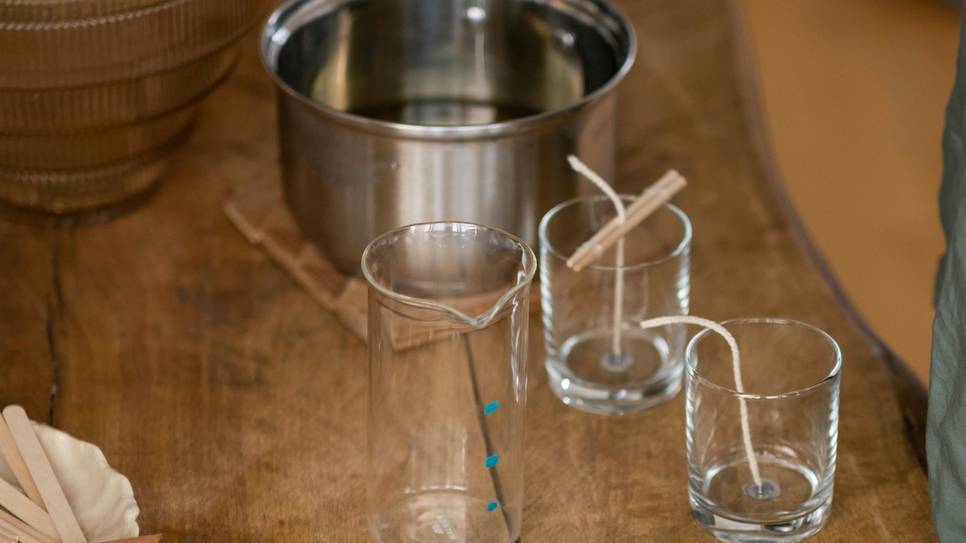 glass jars on a wooden table with candle wicks inside