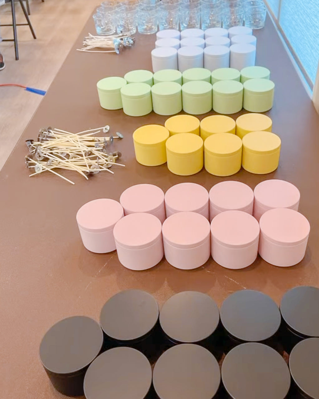Colorful candle tins on a table with sticks and small containers.