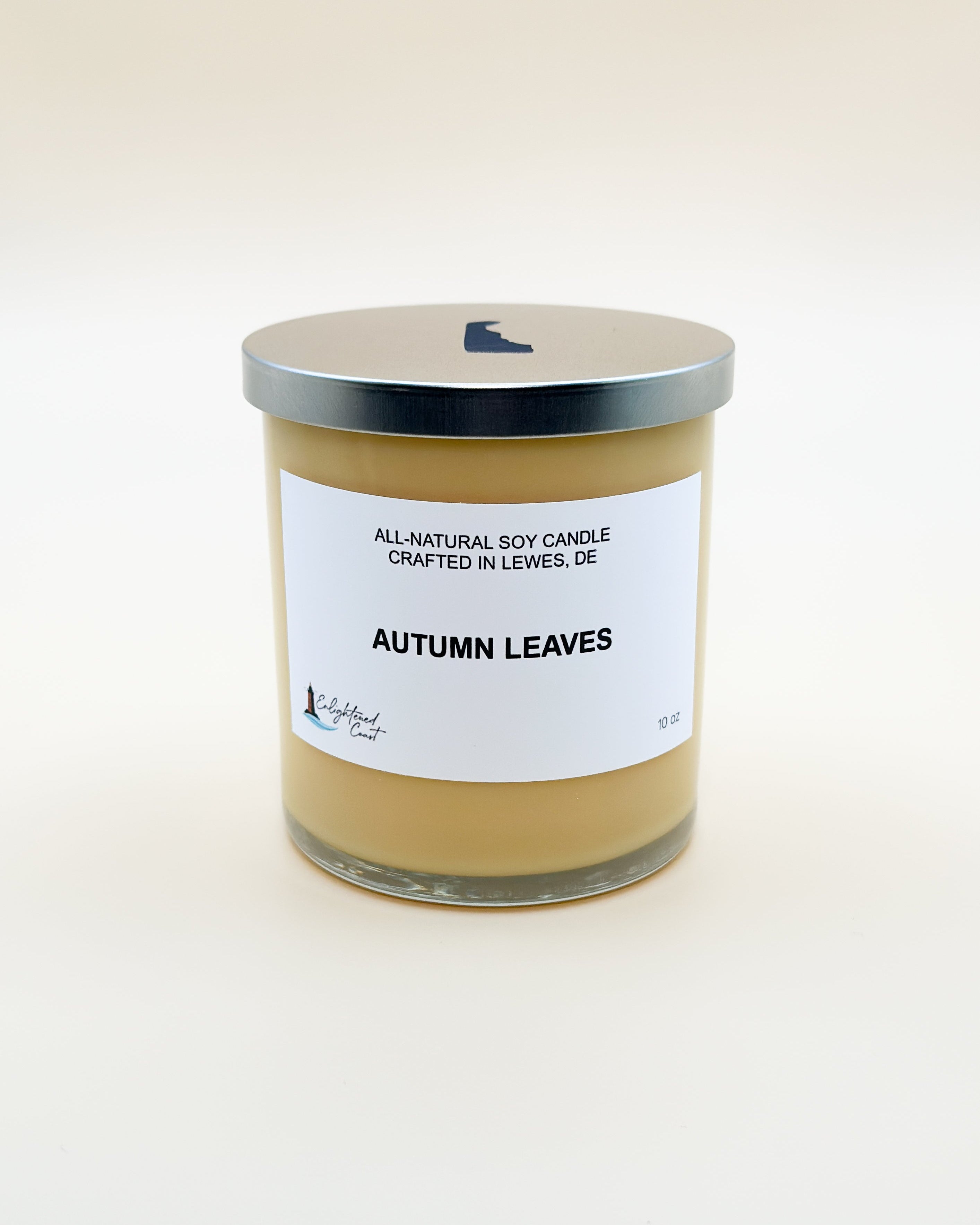 Candle labeled 'Autumn Leaves' with a silver lid on a white background