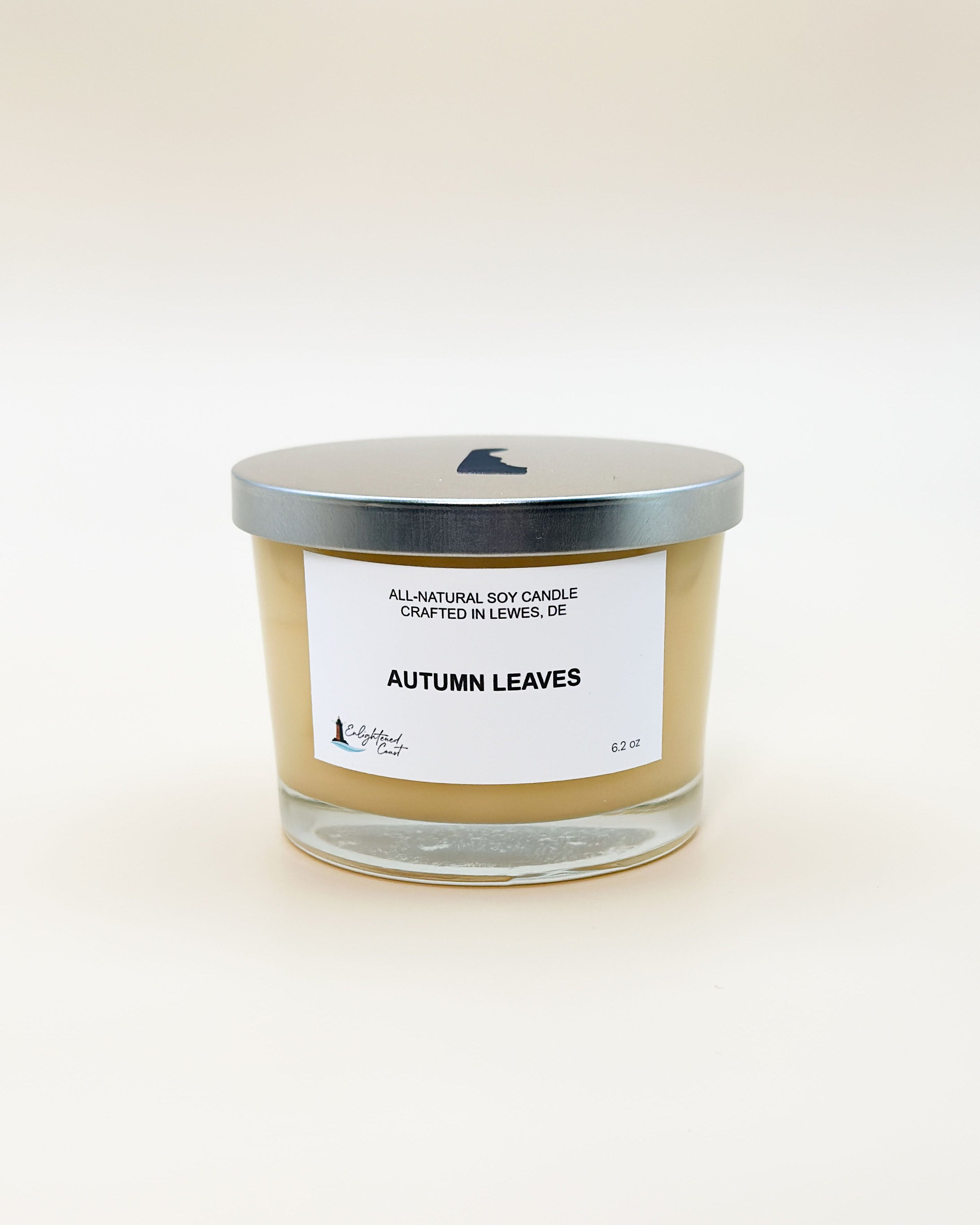 Candle labeled 'Autumn Leaves' with a silver lid on a white background