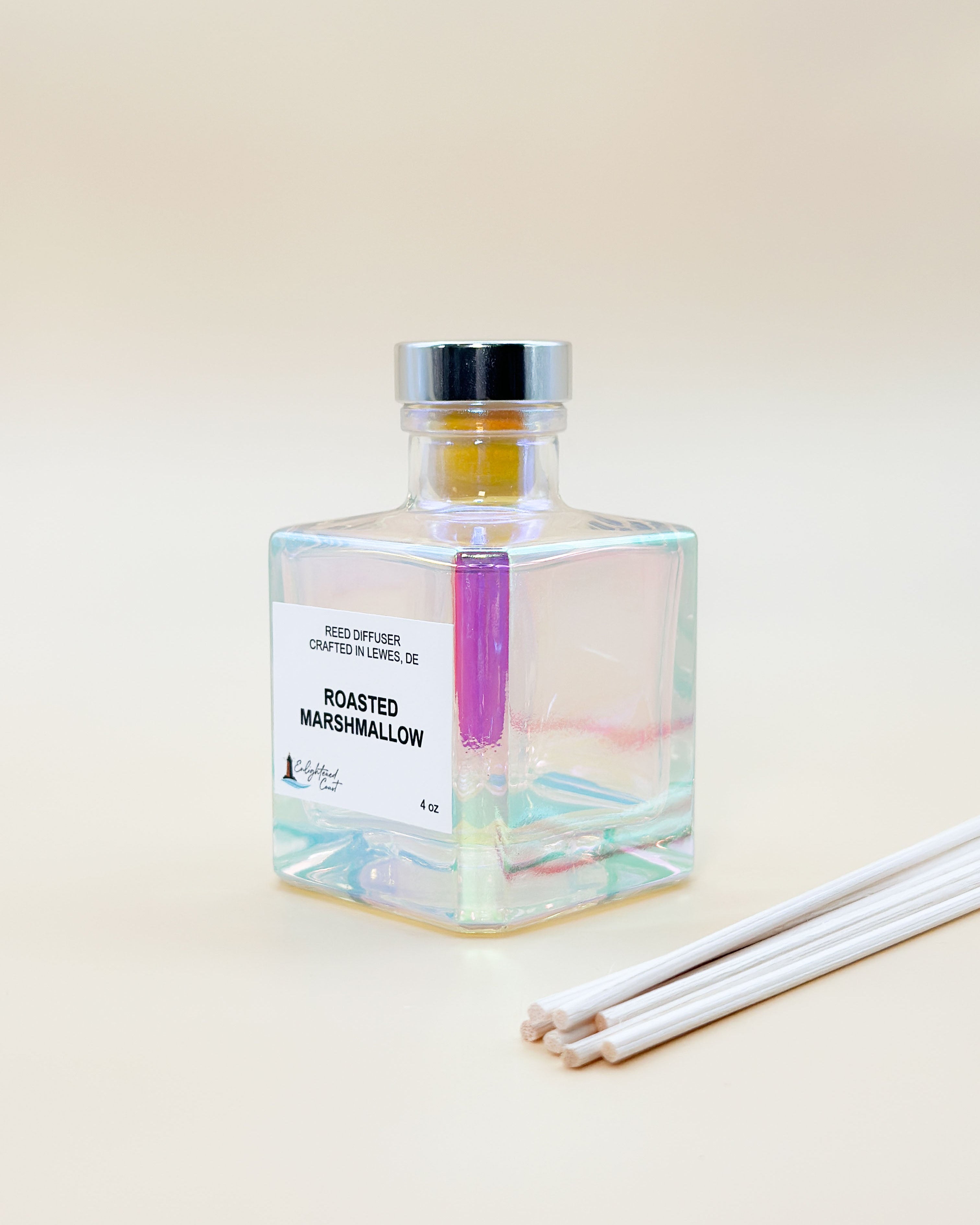 Glass diffuser bottle labeled 'Roasted Marshmallow' with sticks on a beige background