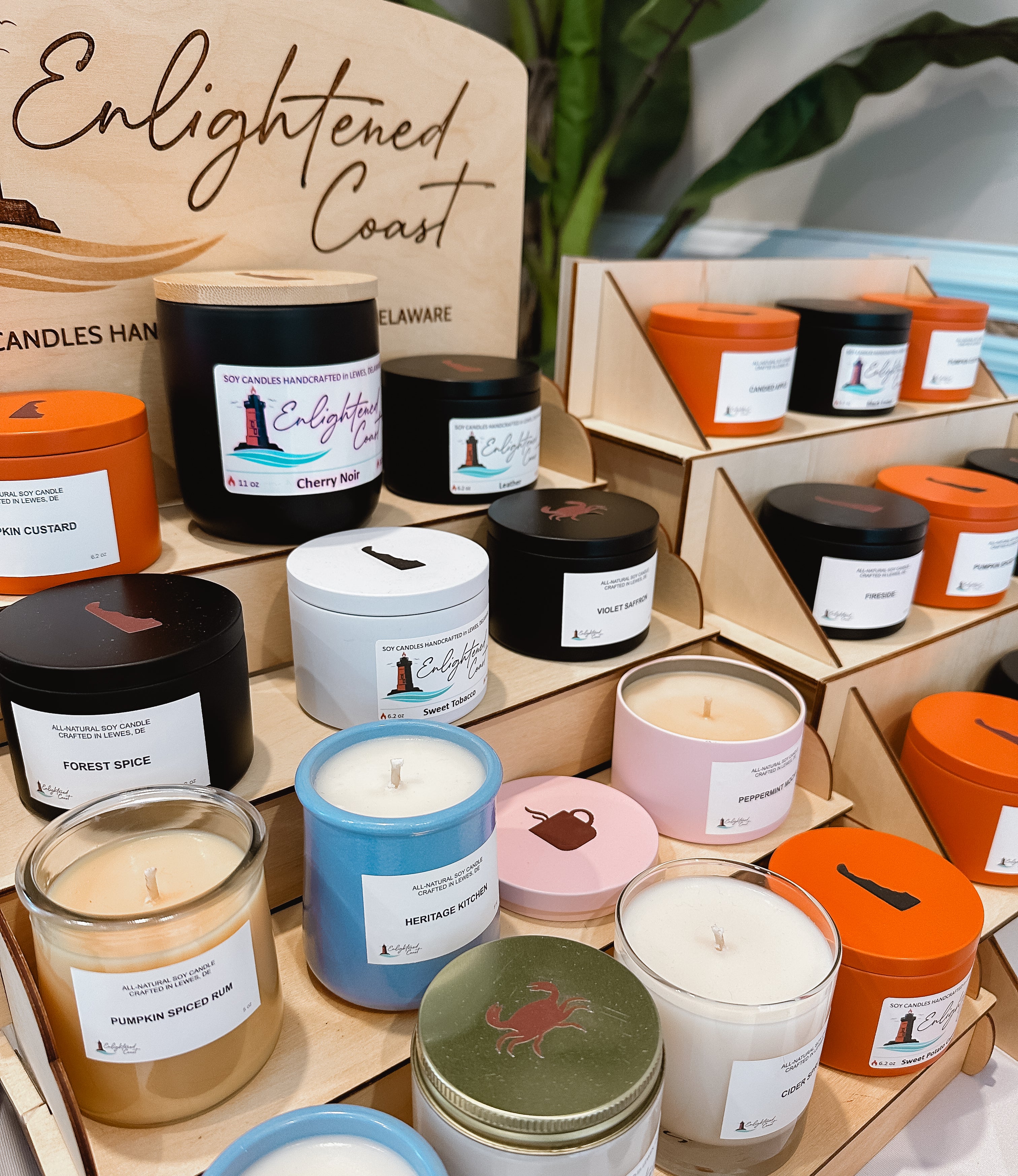 Display of candles with 'Enlightened Coast' branding in a store setting.