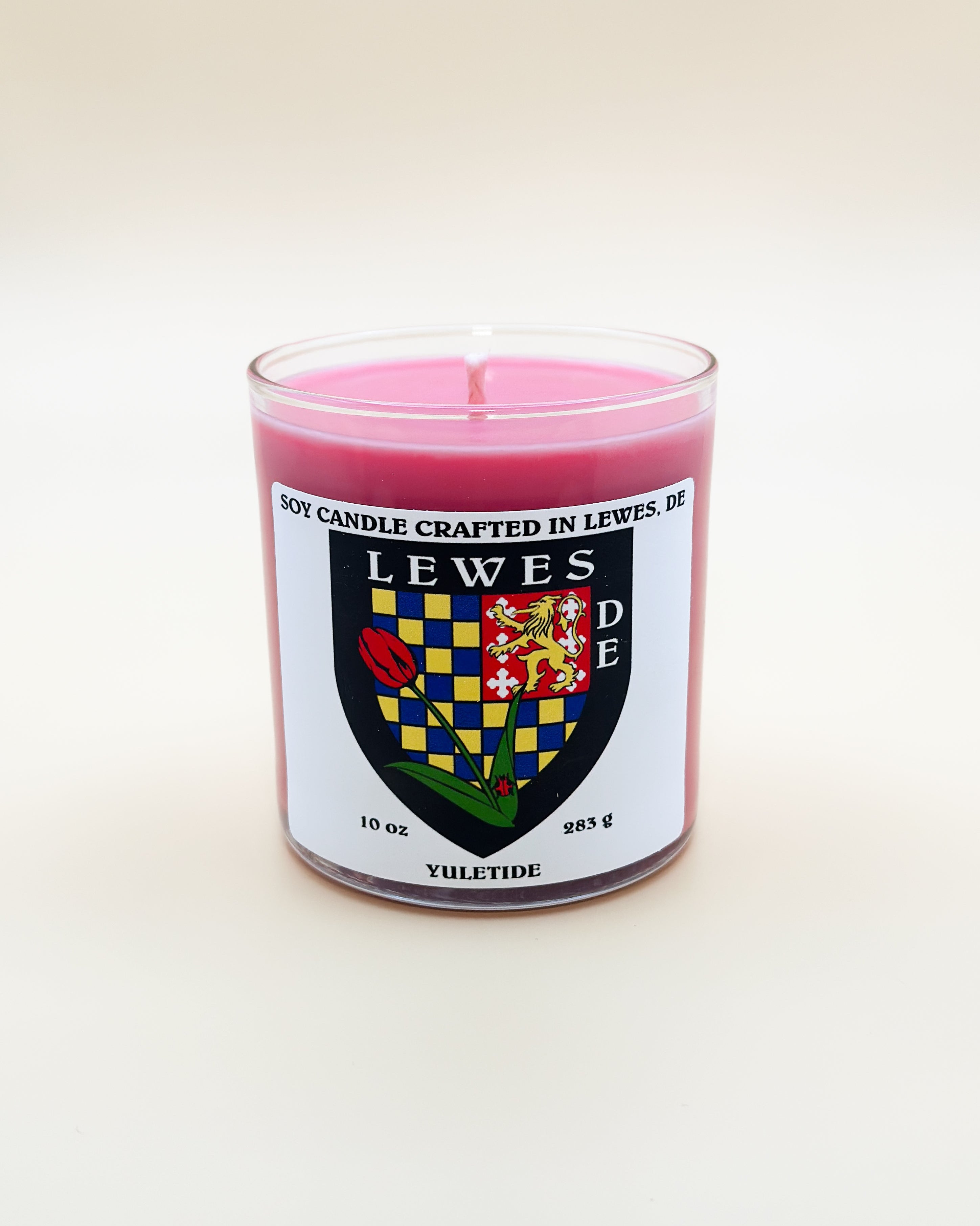 Pink candle with a label featuring a crest on a white background