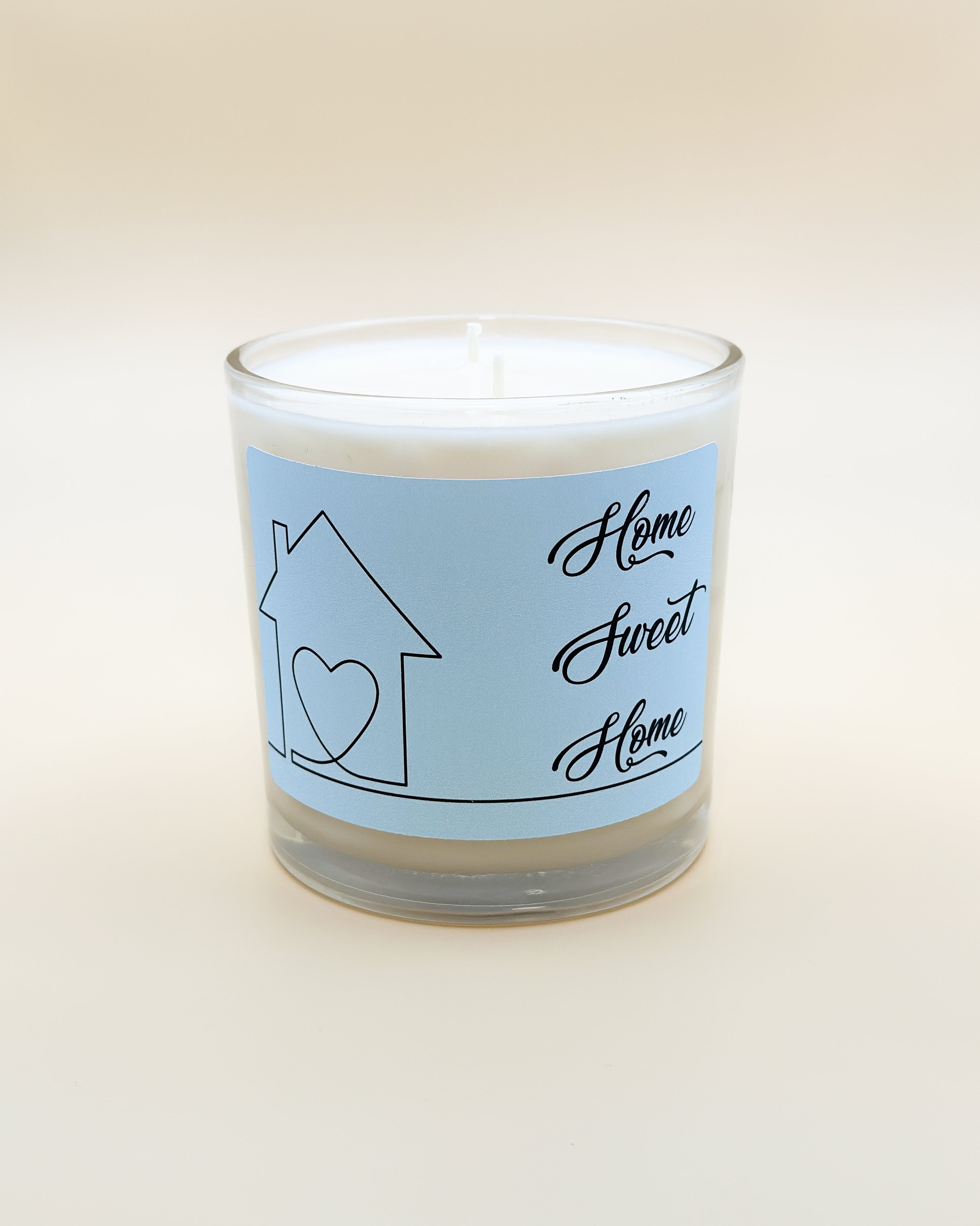 Candle with a custom label featuring a house and heart design on a white background