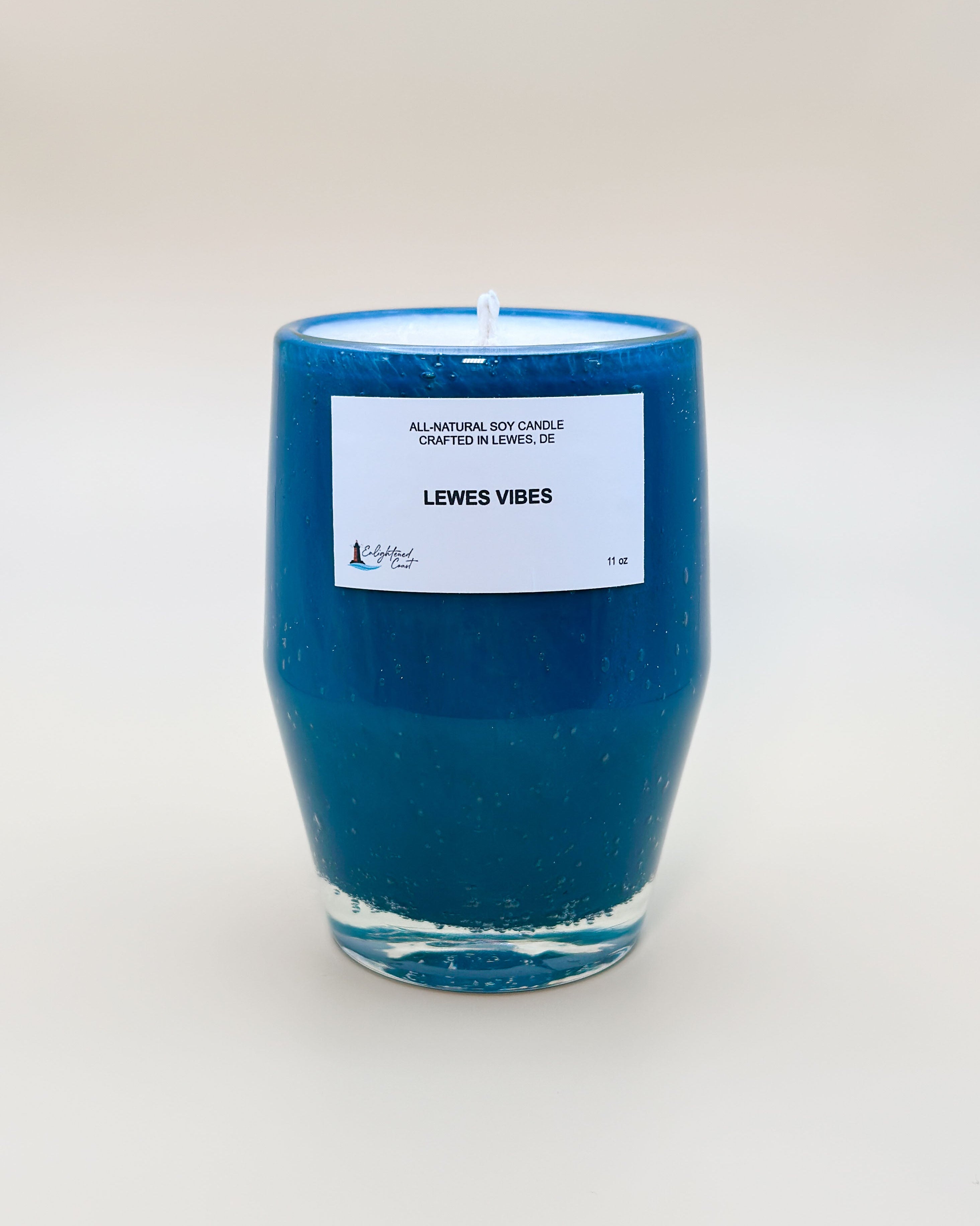 Teal candle with a white Lewes Vibes label