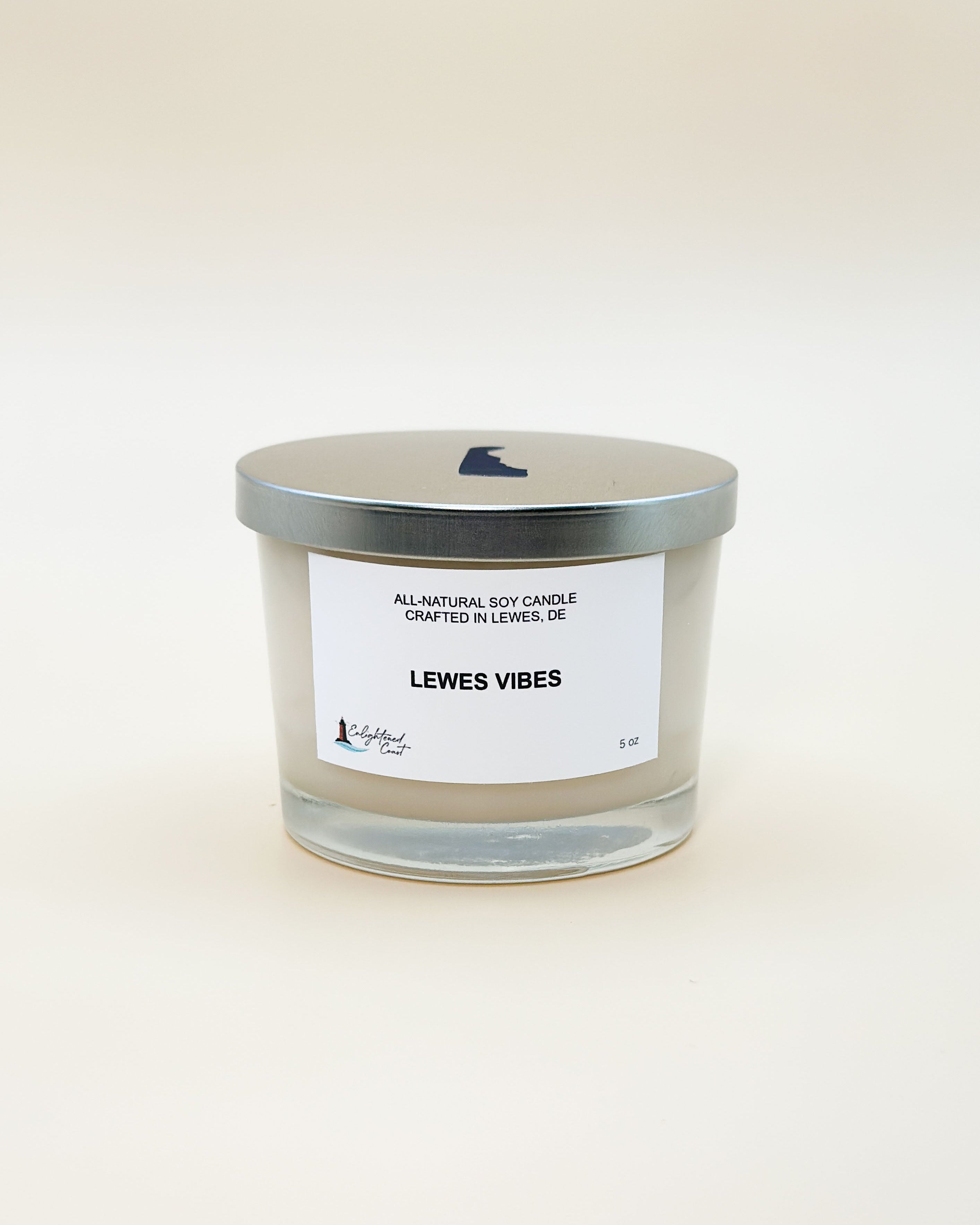 Clear candle with silver lid and white label 'Lewes Vibes' on a light beige background