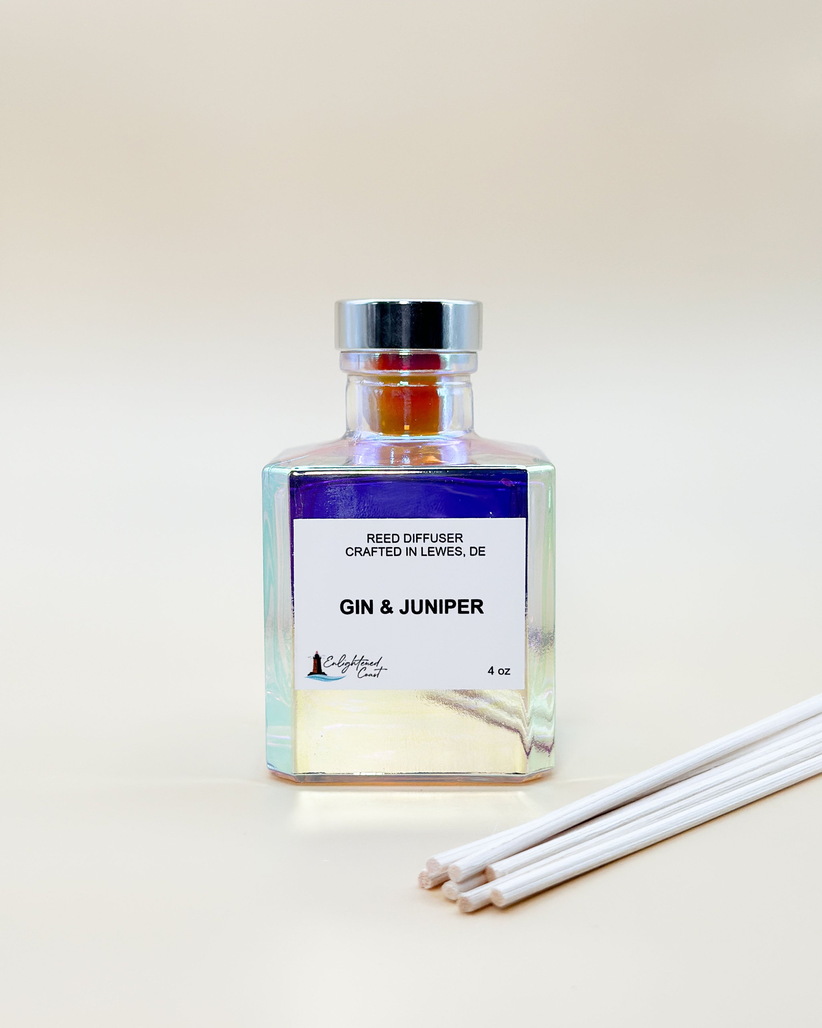 Reed diffuser bottle labeled 'Gin & Juniper' with reeds on a light background