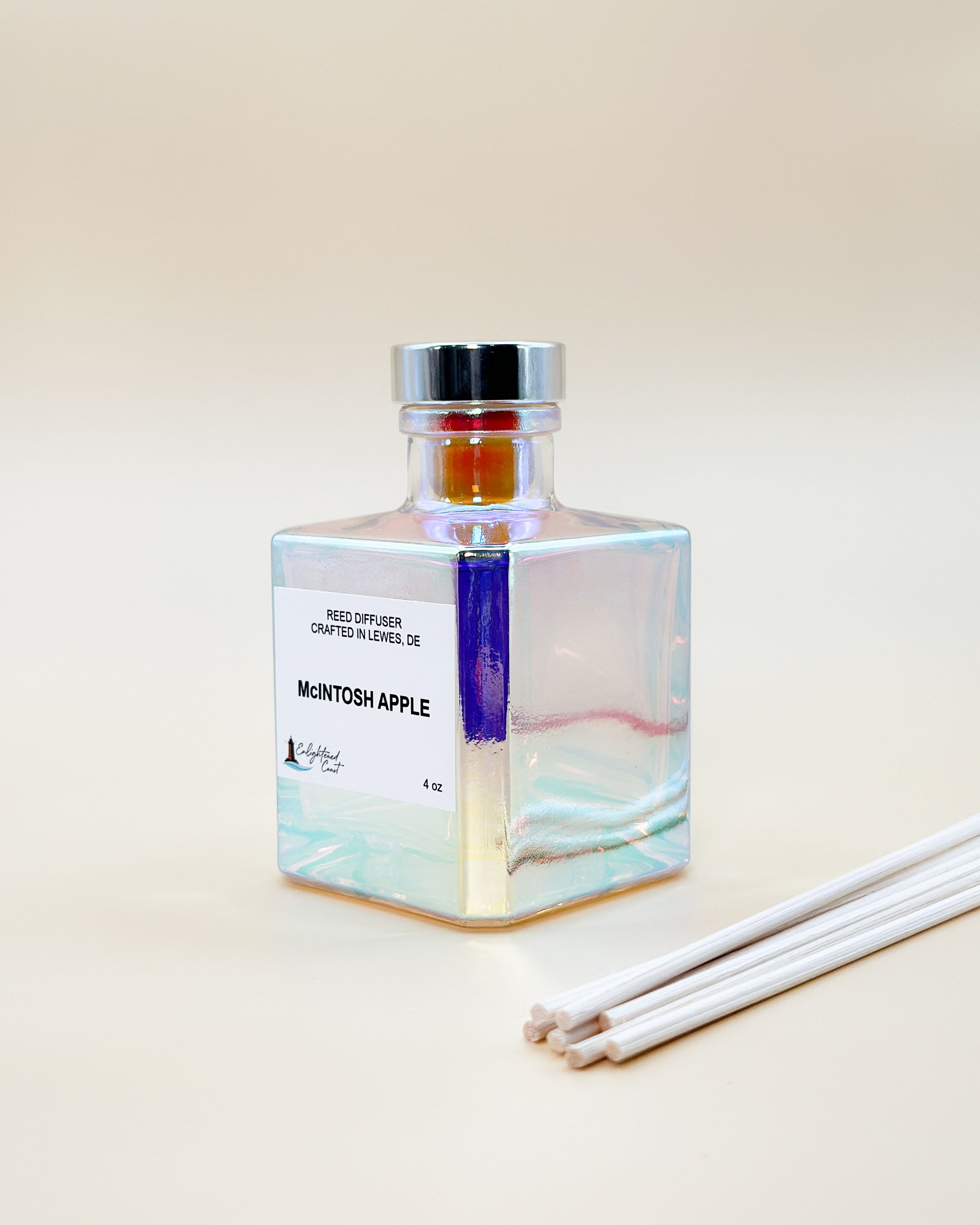 Square glass diffuser bottle with silver cap and white sticks on a beige background