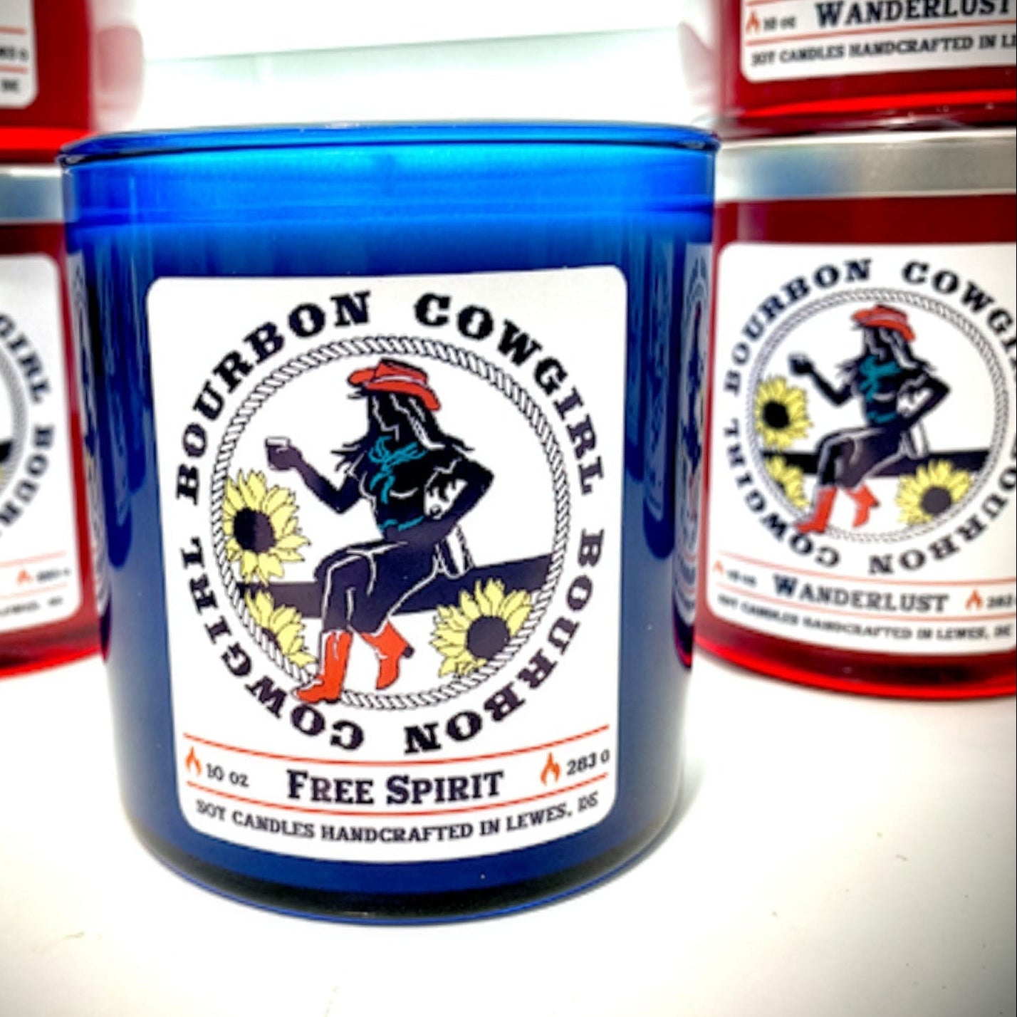 Collection of Bourbon Cowgirl candles with colorful labels on a white background